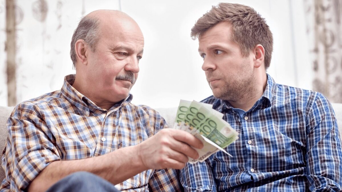 an elderly father gives money to his adult son