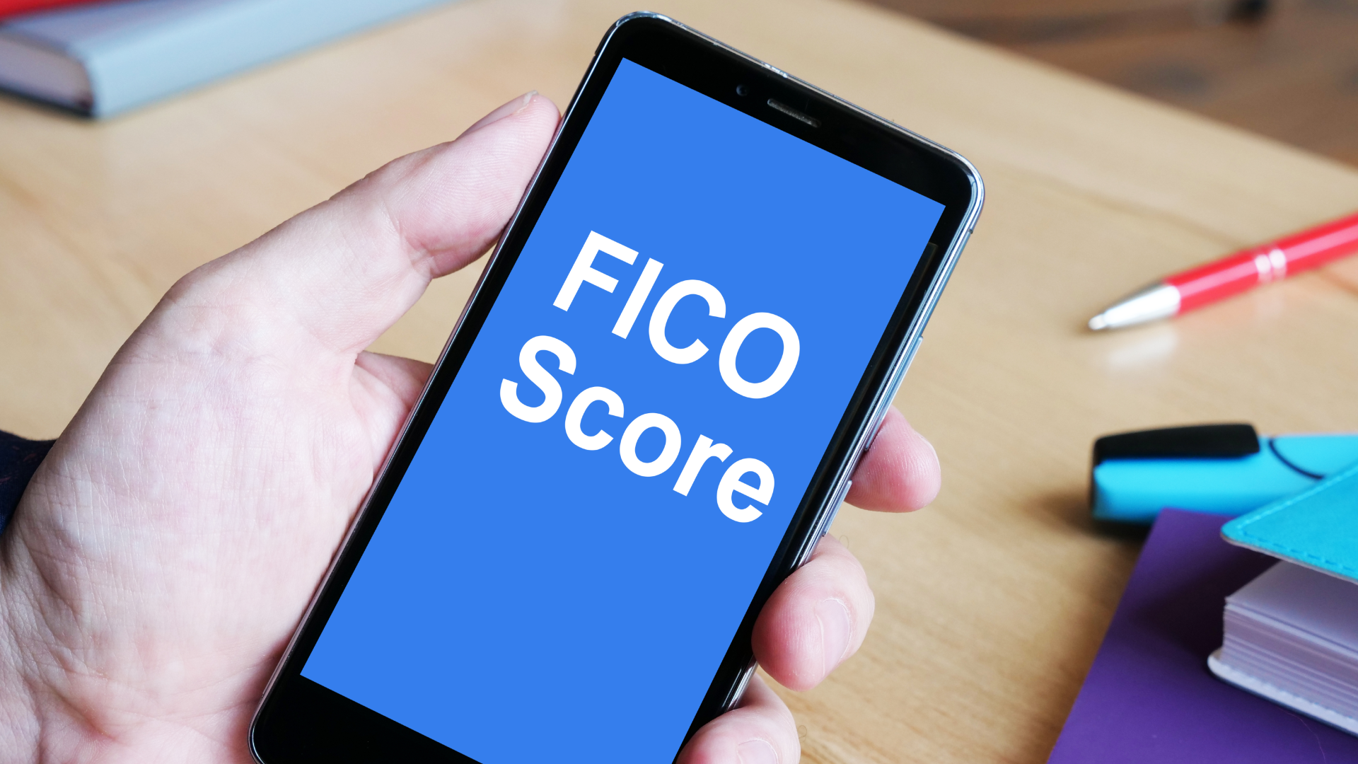 a mobile smartphone displays the words, “FICO Score.”">