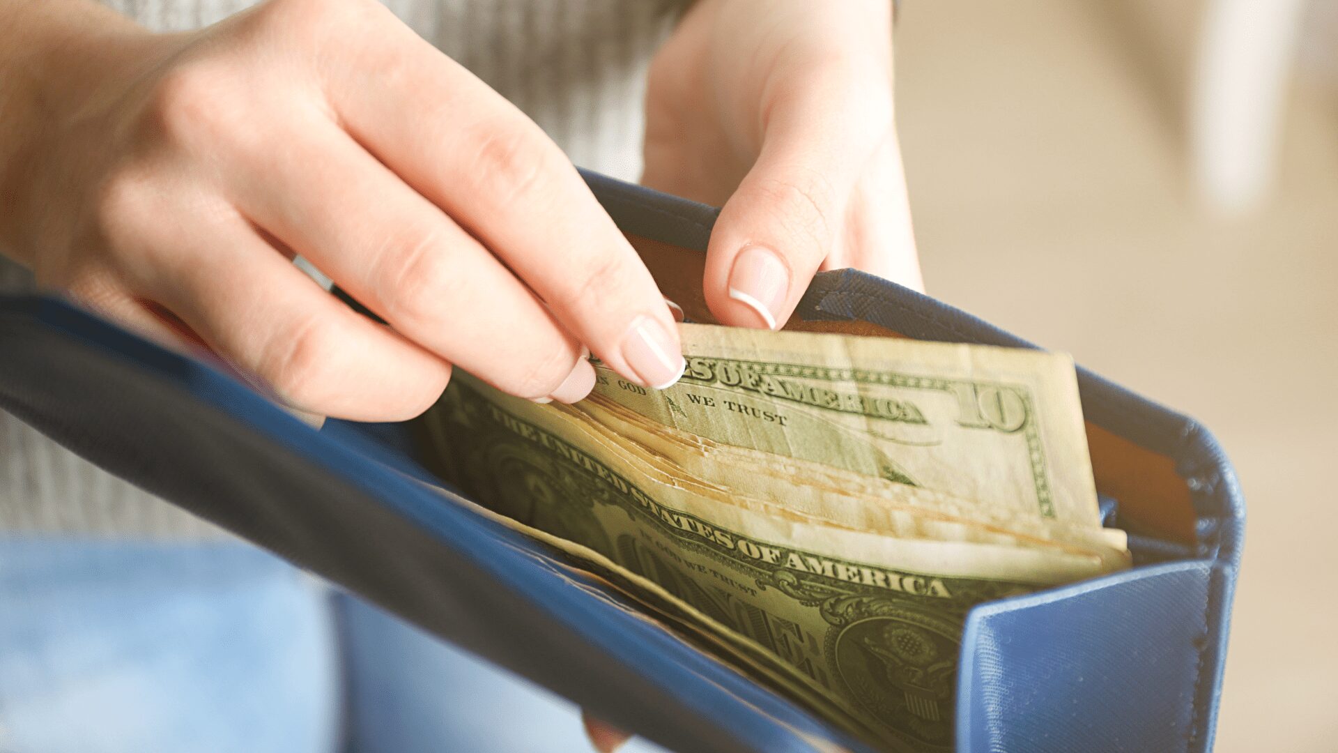 hand with blue wallet full of money