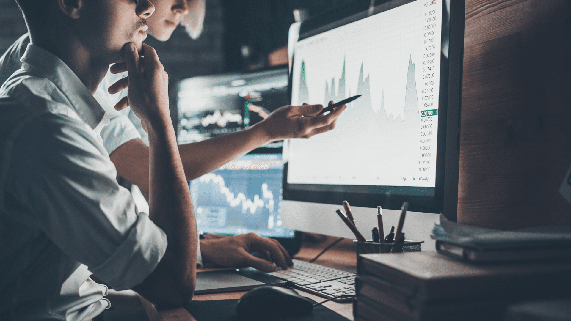 two business people looking at data on computer monitor
