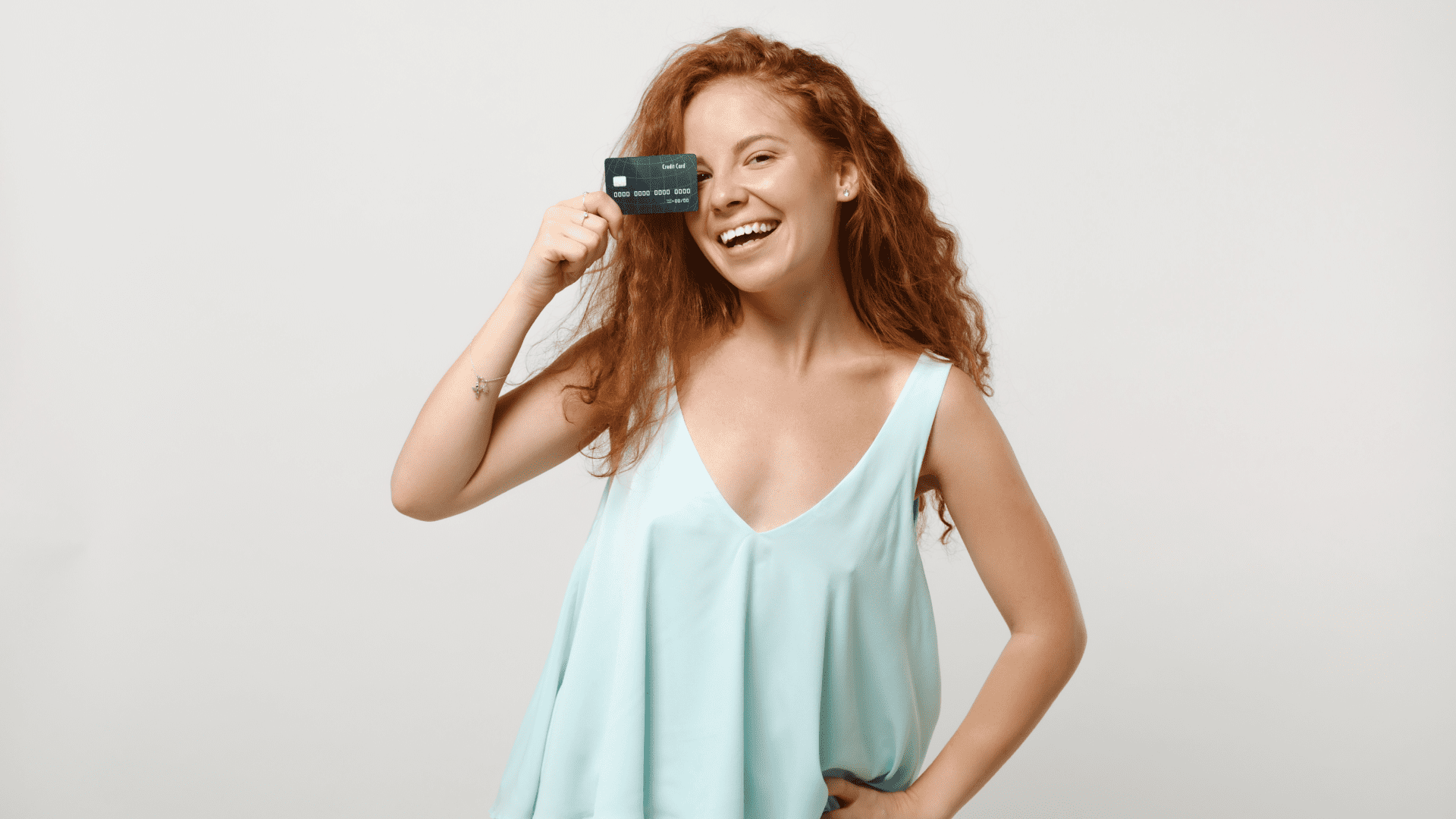 young redhead woman laughing and holding credit card