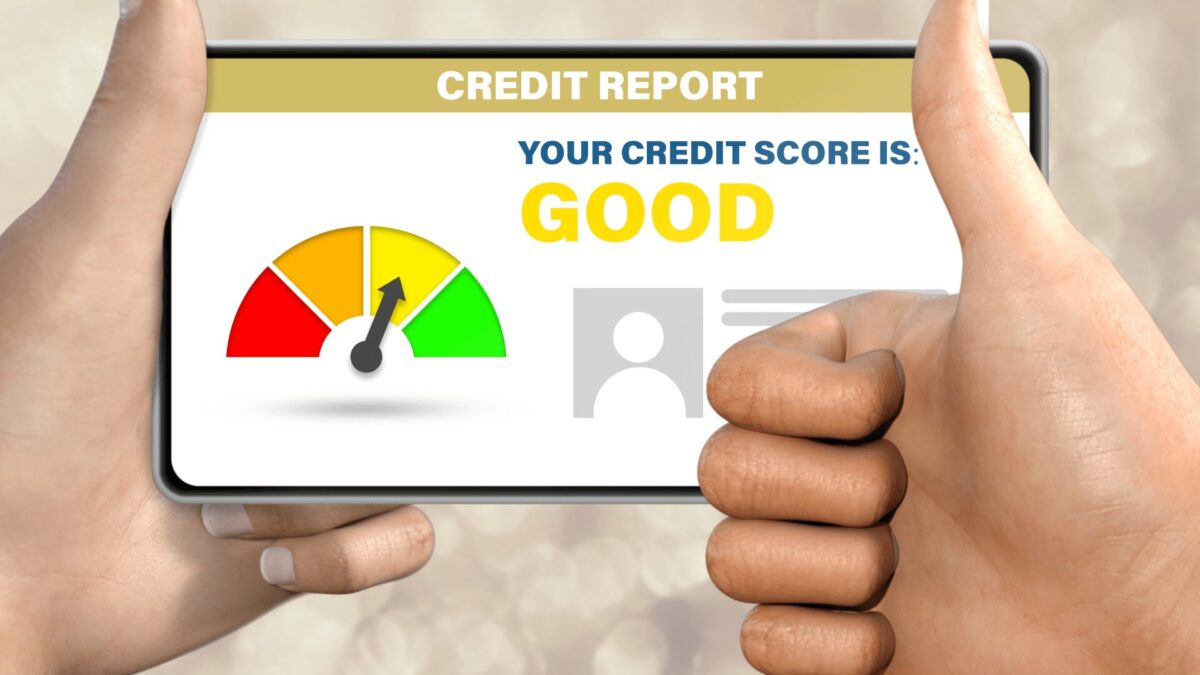 a person gives a thumbs up as they hold a smartphone with a good credit score on display