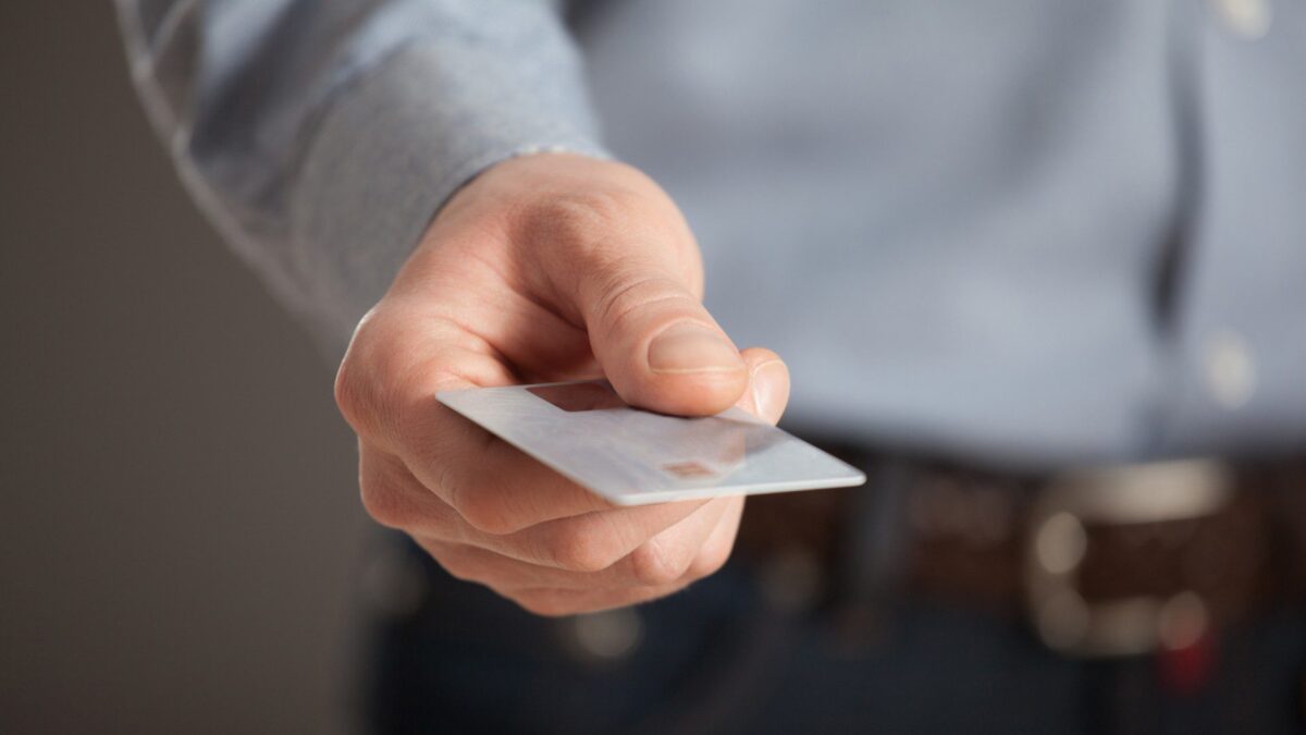 a person’s hand holds out a qualified debit card for instant funding