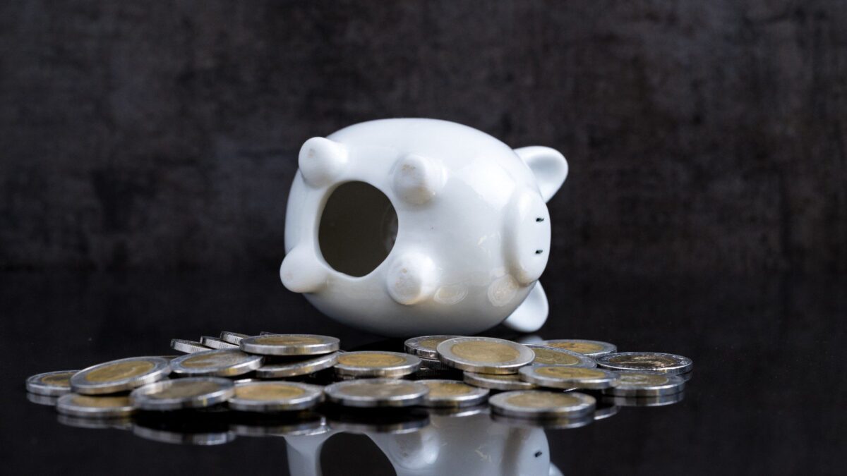 a tipped over piggy bank with money coming out of it