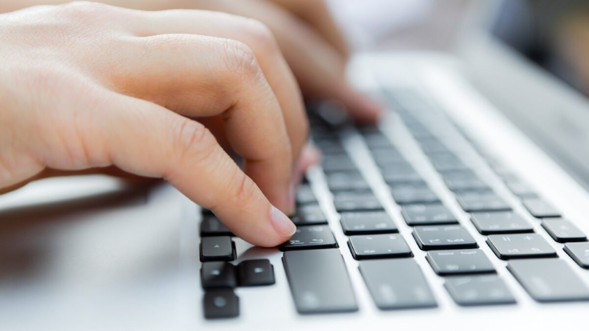 Close-up das mãos de um homem digitando em um teclado de computador