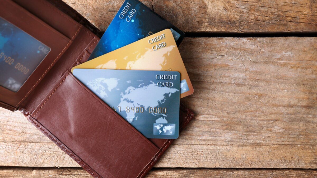 Cartão de crédito saindo da carteira indicando que você deve manter a conta antiga aberta