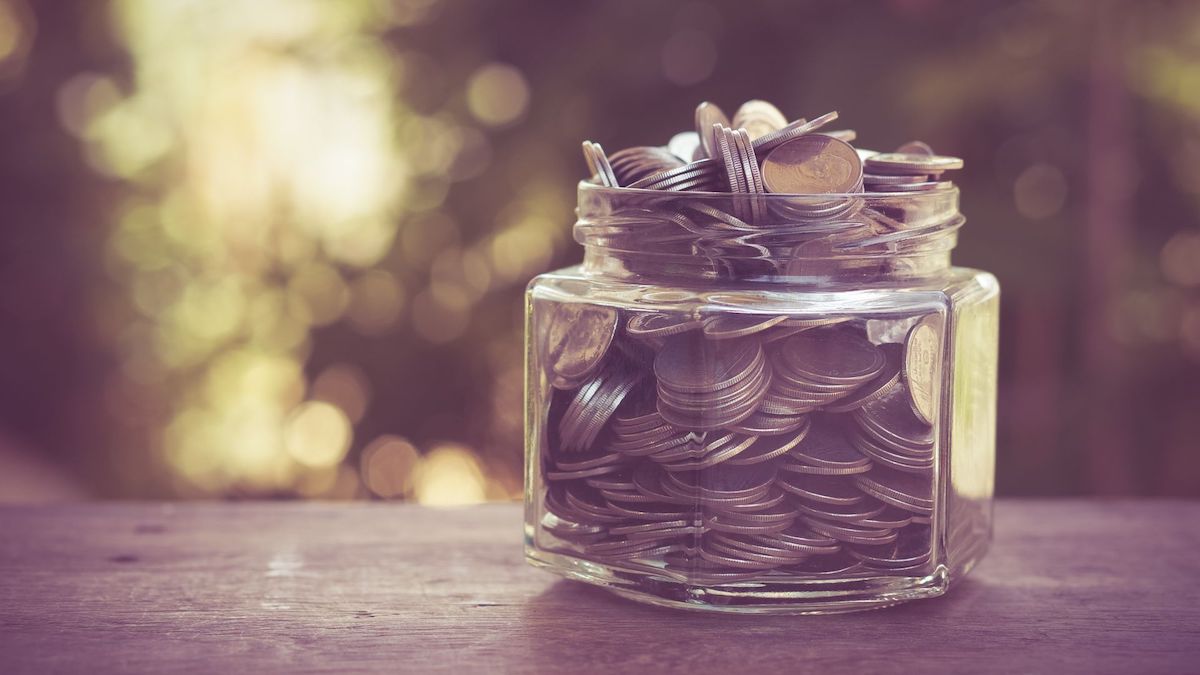 Jar full of coins sitting on porch ledge with blurred background | Wise Loan