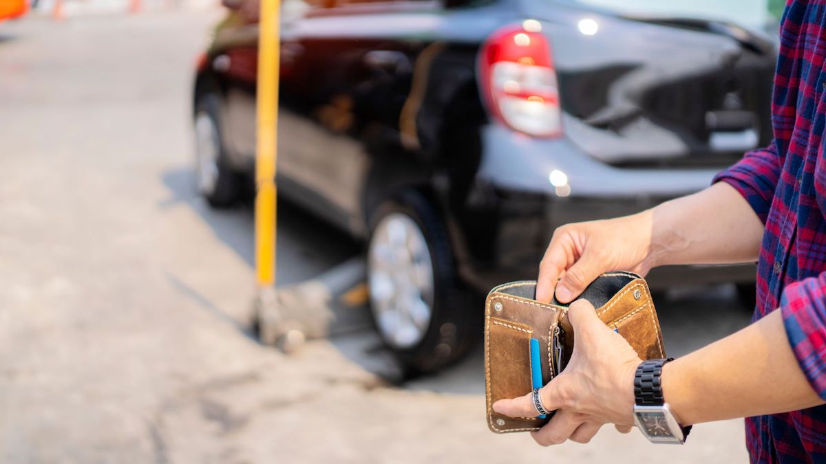 Person with flat tire opening their empty wallet on the side of the road | Wise Loan