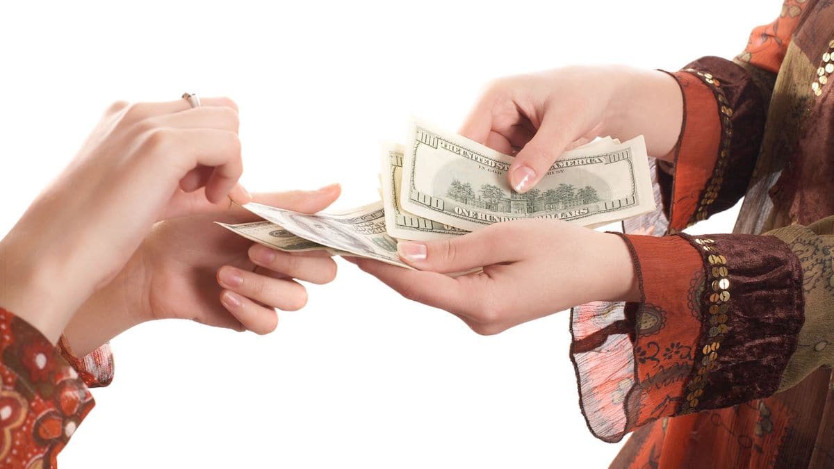 Close up of female hands exchanging hundred-dollar bills | Wise Loan