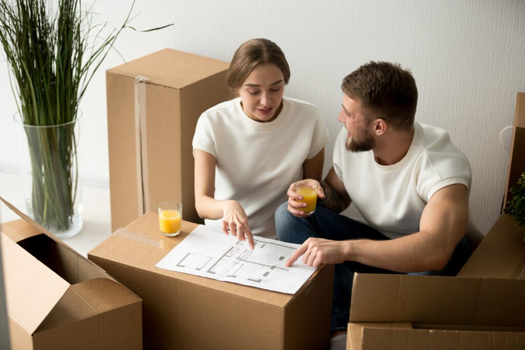 Couple reviews paperwork resting on cardboard box while applying for loan | Home repair financing