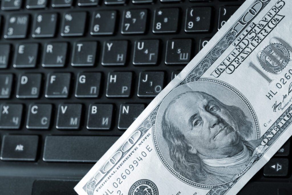 Close up of hundred dollar bill laying across black keyboard | Auto repair financing options