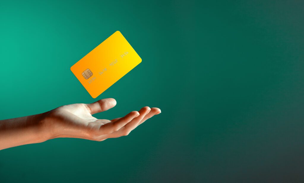 Yellow credit card hovers over open hand in green room | Funeral financing options