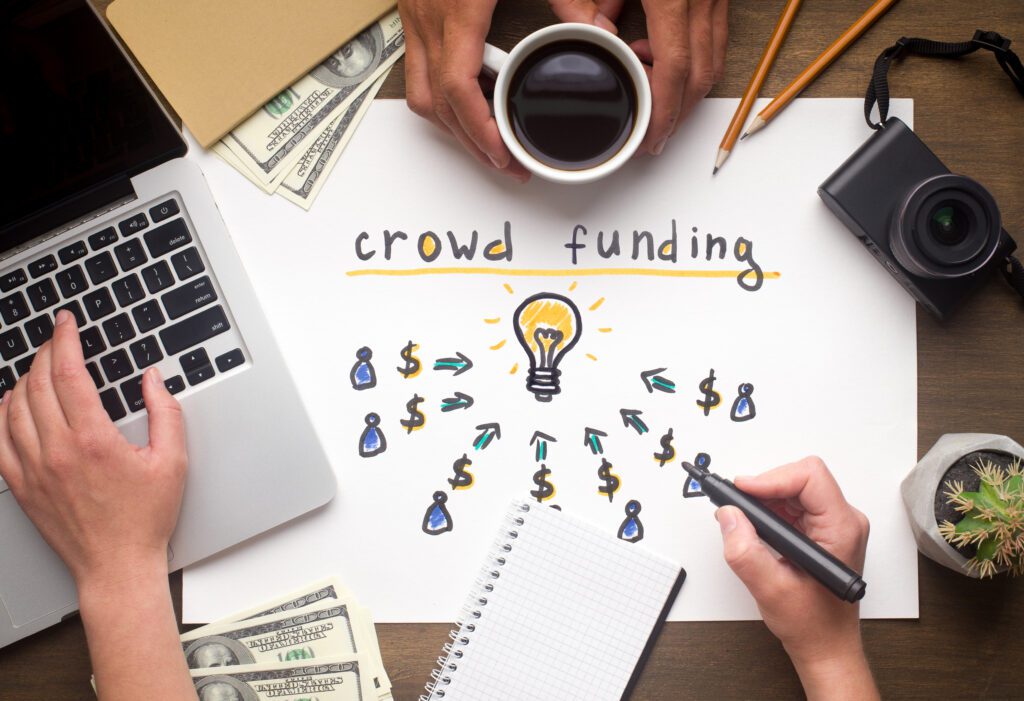 Two people sit at desk with laptop to collaborate on crowdfunding plan | Funeral financing options