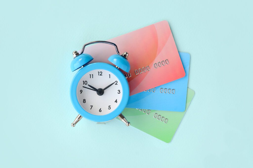 Blue alarm clock rests on top of three credit cards | Funeral financing options