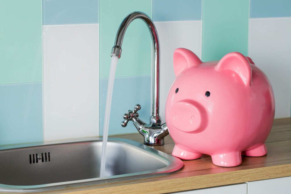 Piggy bank rests next to running kitchen sink with blue tile | Home repair financing