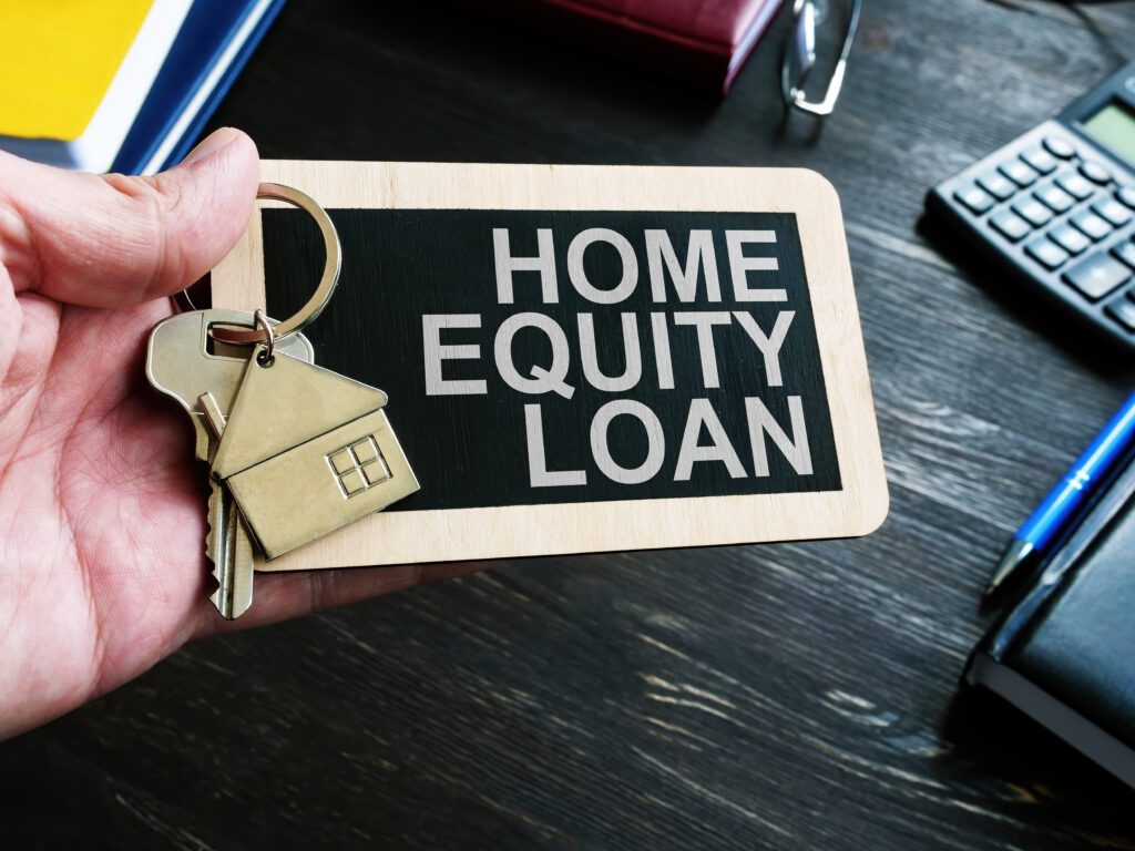 Person holds set of keys over small sign labeled as home equity loan | Home repair financing