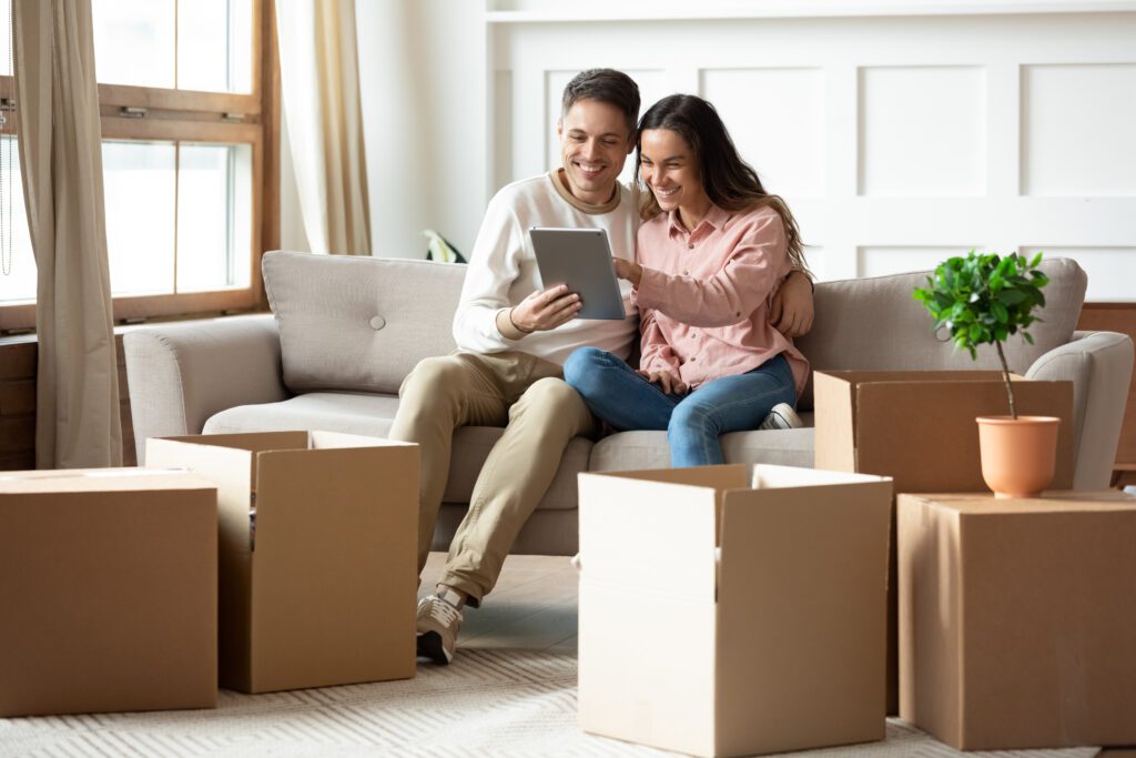 Couple sits on couch with packed moving boxes while applying for loan | Home repair financing
