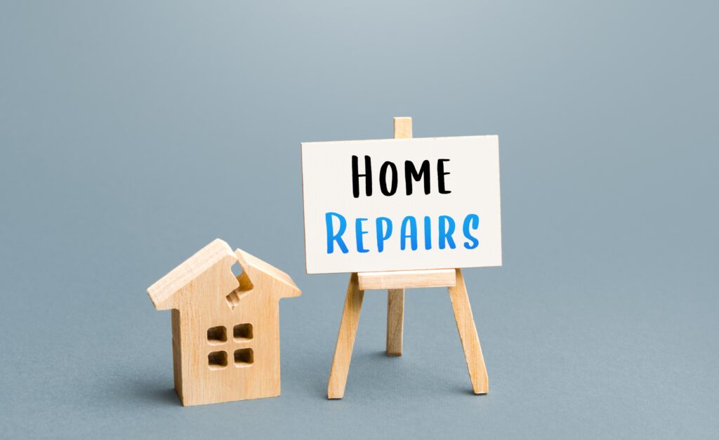 A cracked wooden house next to a sign | How do home repair loans work?