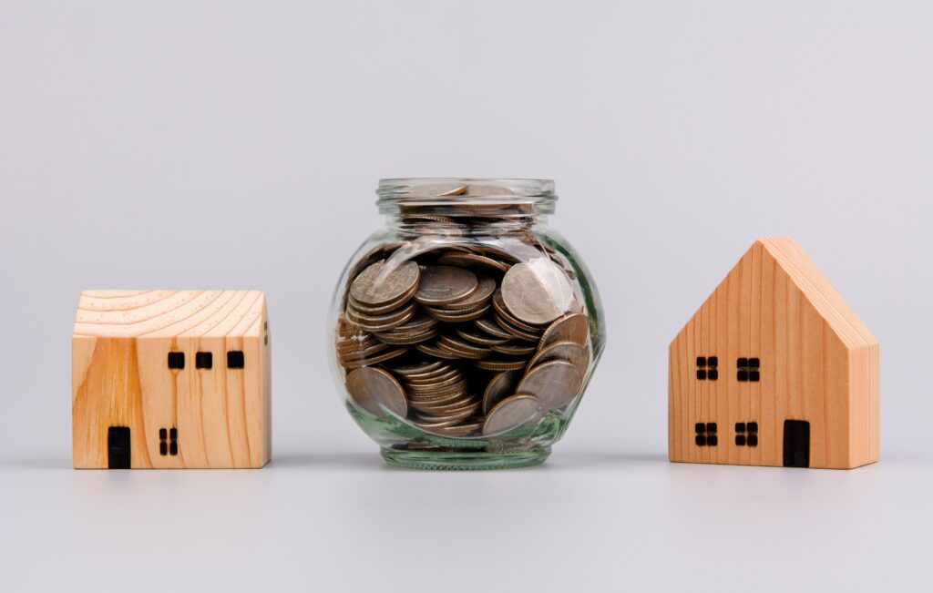 Coins in a glass jar next to a wooden house | How does a relocation loan work?