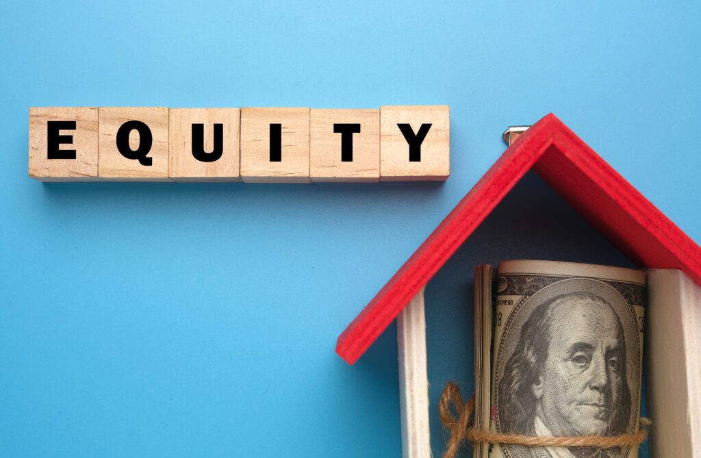 Wooden blocks spell, “Equity,” next to model home with red roof | Relocation financing options