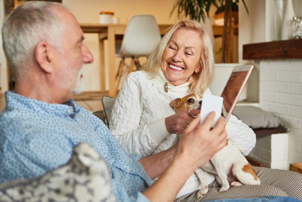 Elderly couple reviews vet bills while sitting on their couch with a corgi | Veterinarian loan financing