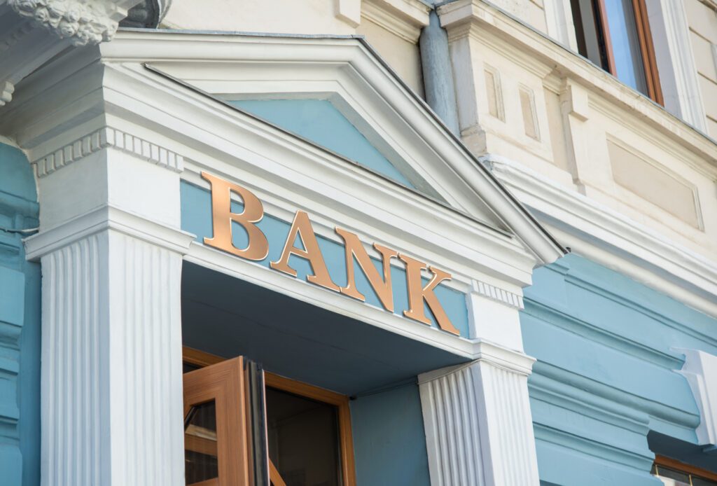 Gold sign advertises bank on the side of a stone building | Veterinarian loan financing