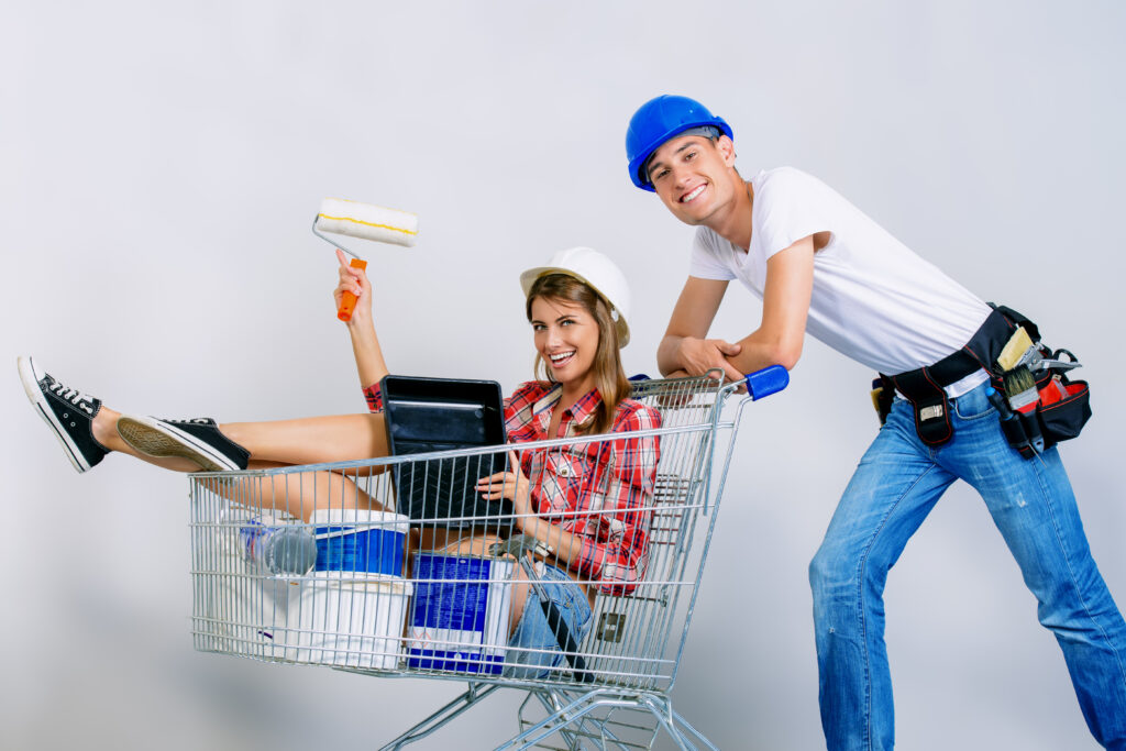 Man in blue hard hat pushes woman in cart holding painting supplies | How to get a home repair loan