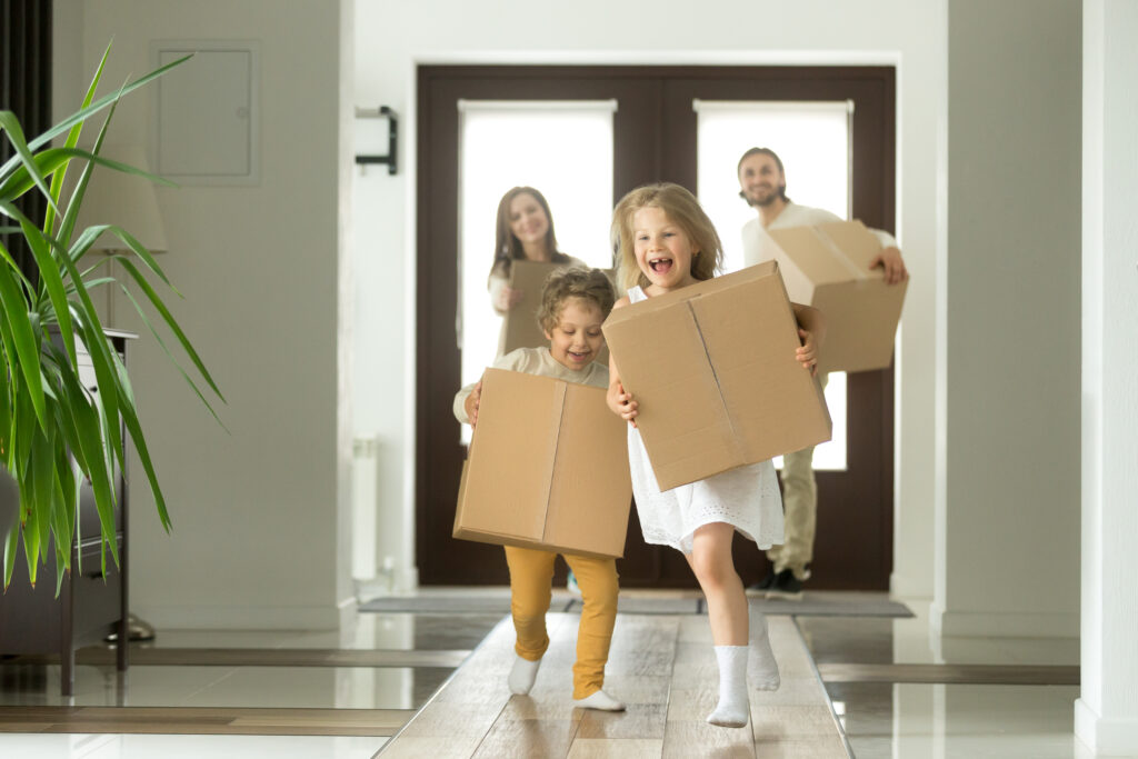 Smiling children holding boxes run into new home as parents trail behind them | How to get a moving loan