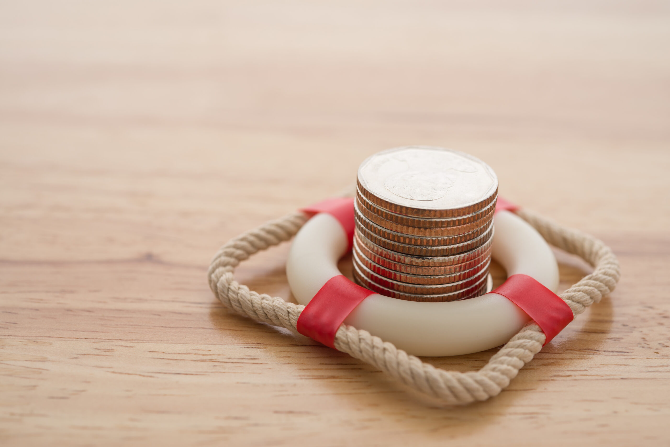 Coin stack surrounded by life preserver on yellow background | 9 types of emergency loans