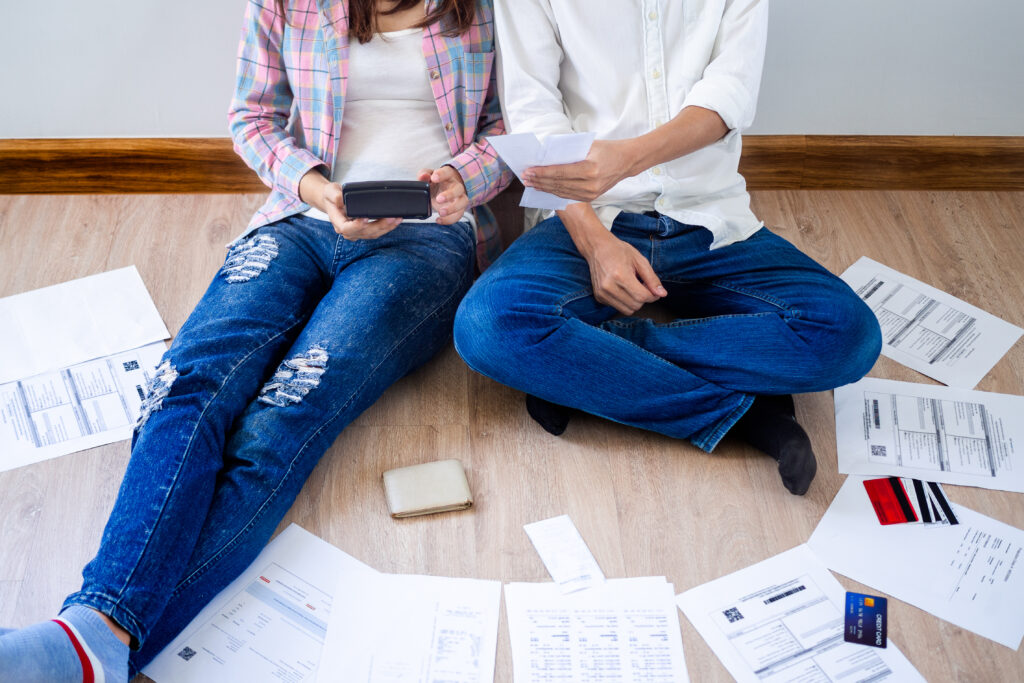 Couple sitting on floor against a wall while reviewing emergency expenses | Best emergency loans for bad credit