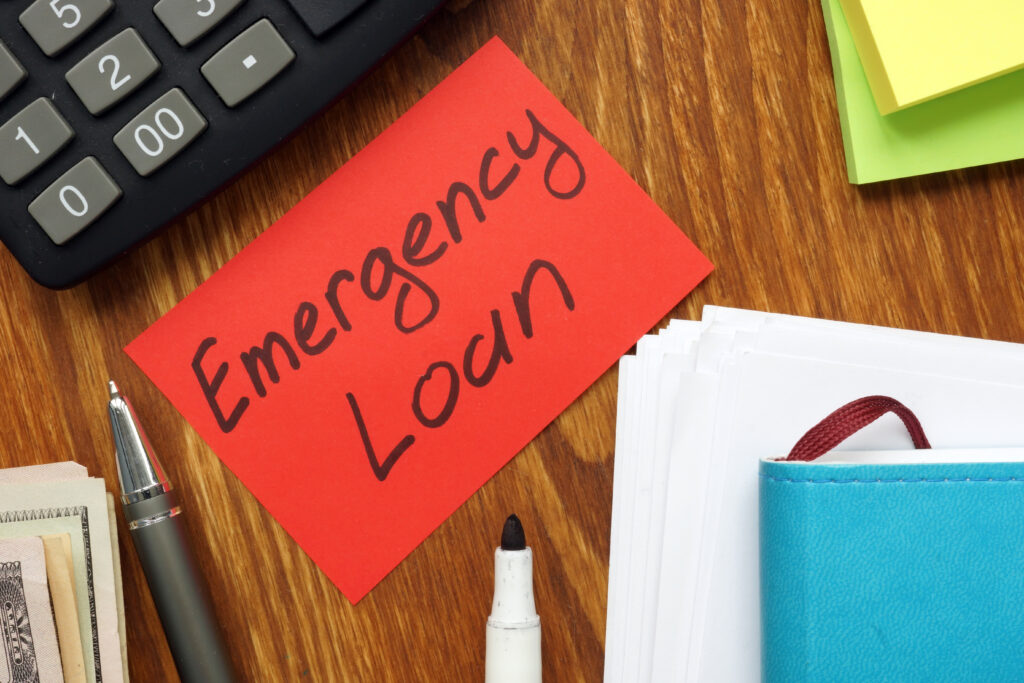 Red sticky note labeled as emergency loan rests on wooden desk | Best emergency loans