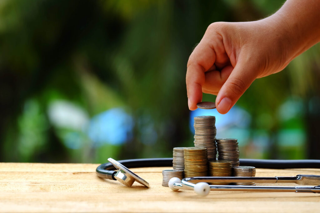 Close-up of person placing quarter on coin stack surrounded by stethoscope | How to get a medical loan