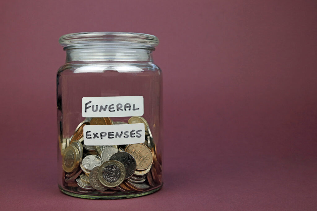 Jar of coins labeled as funeral expenses rests on red background | How to get a funeral loan