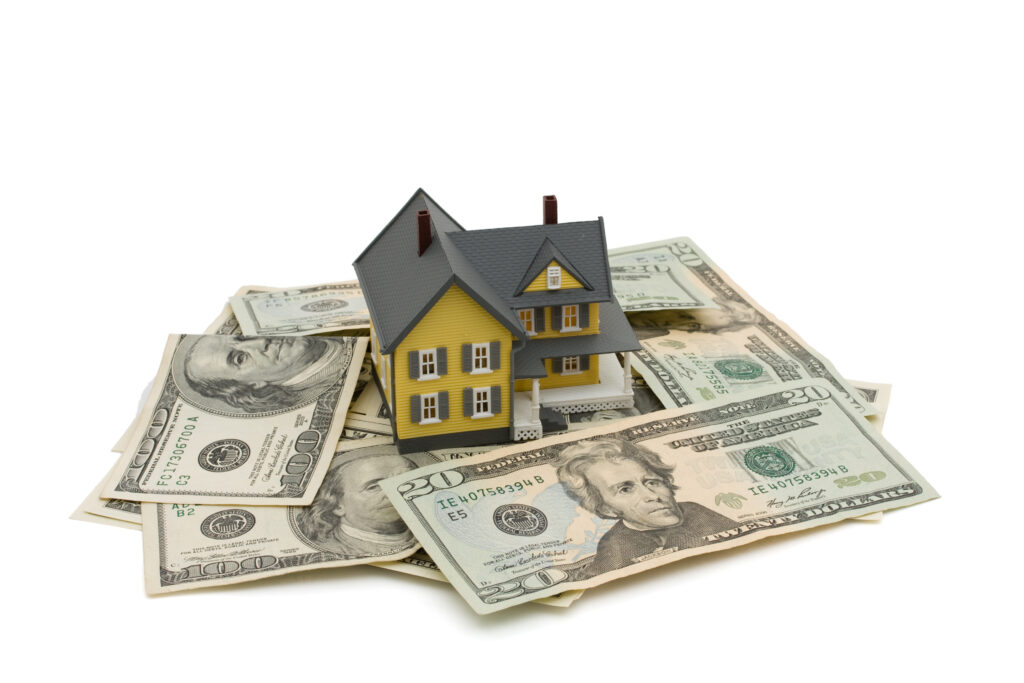 Yellow model home rests on stack of cash | How to get a home repair loan