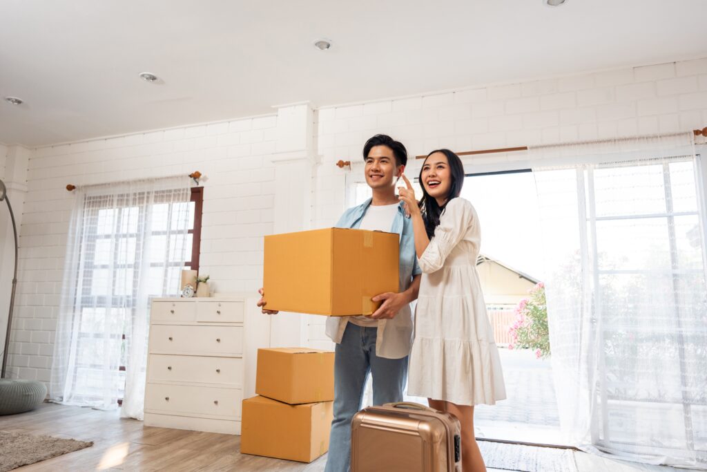 Young couple holding packed box smiles as they enter new home | How to get a moving loan