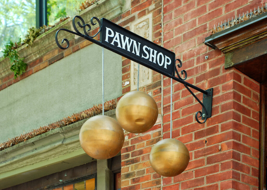 Black sign for pawn shop hangs from side of brick building | 9 types of emergency loans