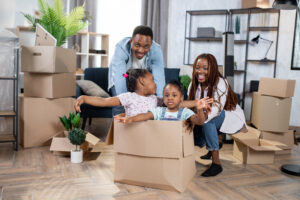 Young couple smiles as they hold two babies playing in cardboard box | How to get a moving loan