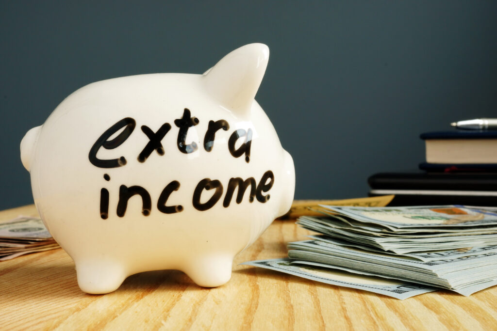 Piggy bank marked as extra income sits next to pile of cash | Planning for unexpected expenses