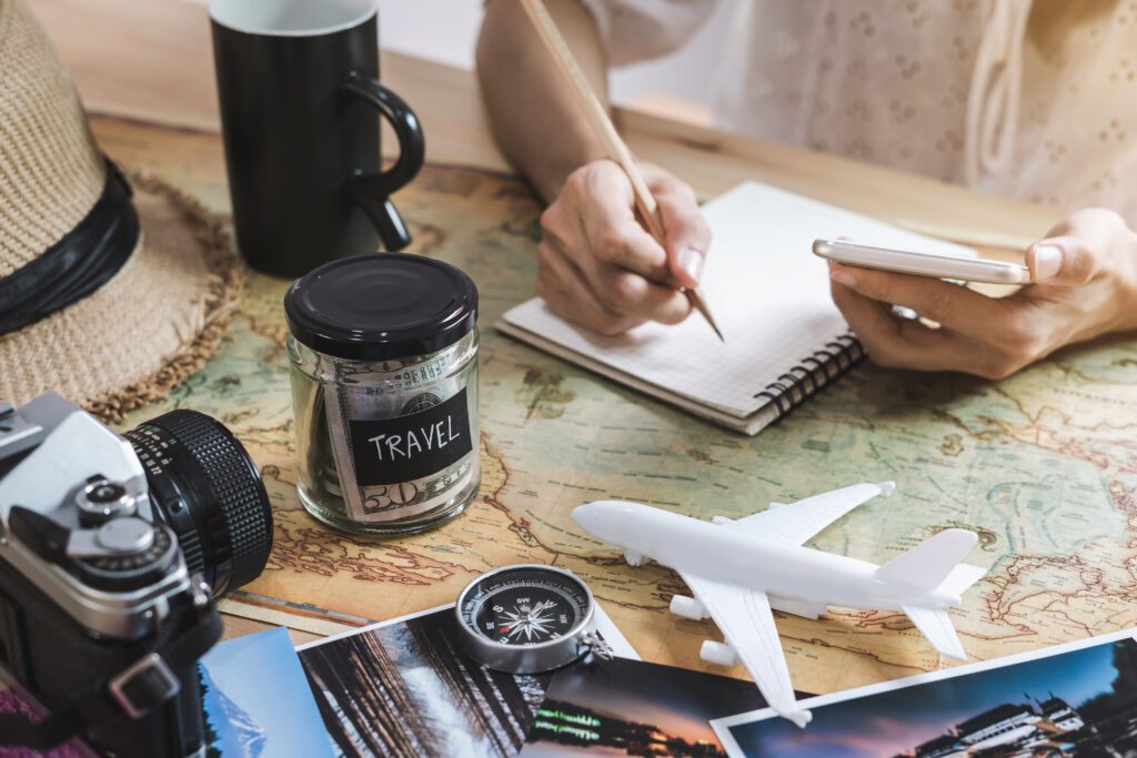 Person planning a vacation on a desk with map, savings jar and calculator | Best Vacation Loans