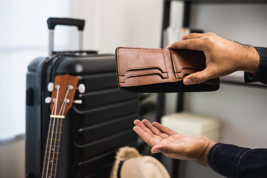 Person holding empty wallet upside down next to carry on suitcase | Best Vacation Loans