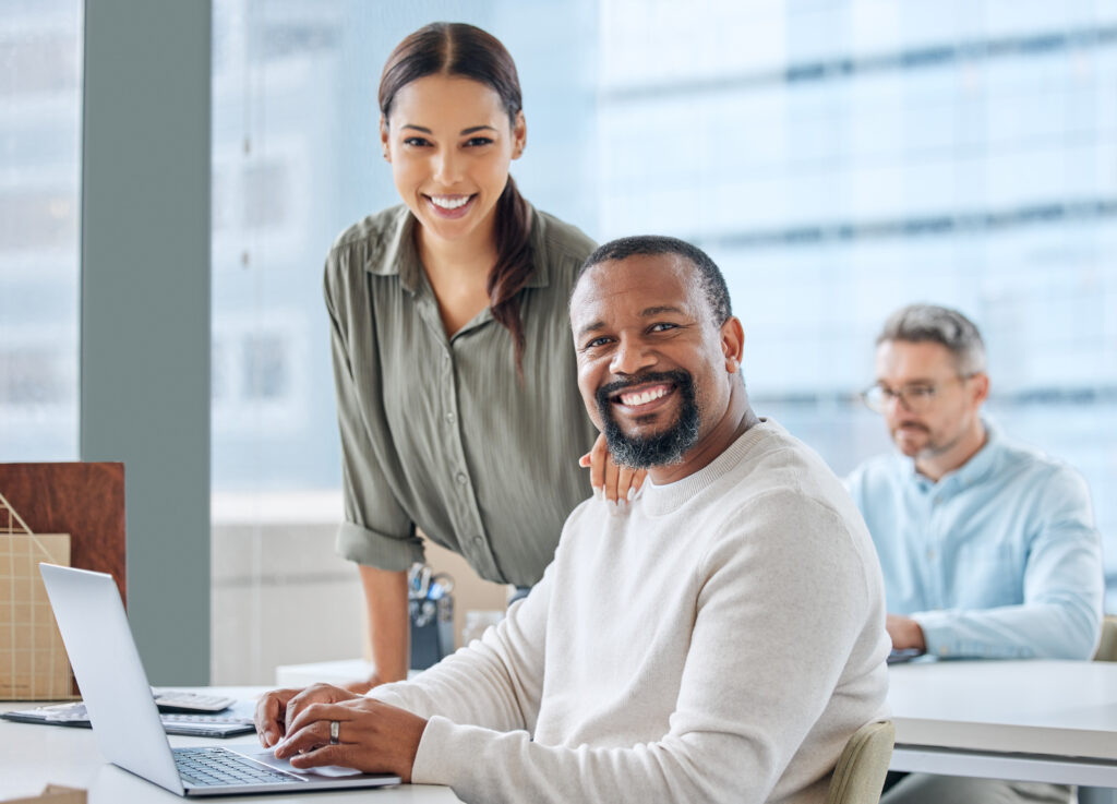 Man Man is used in a white jacket a laptop with a woman in a green shirt standing beside him.